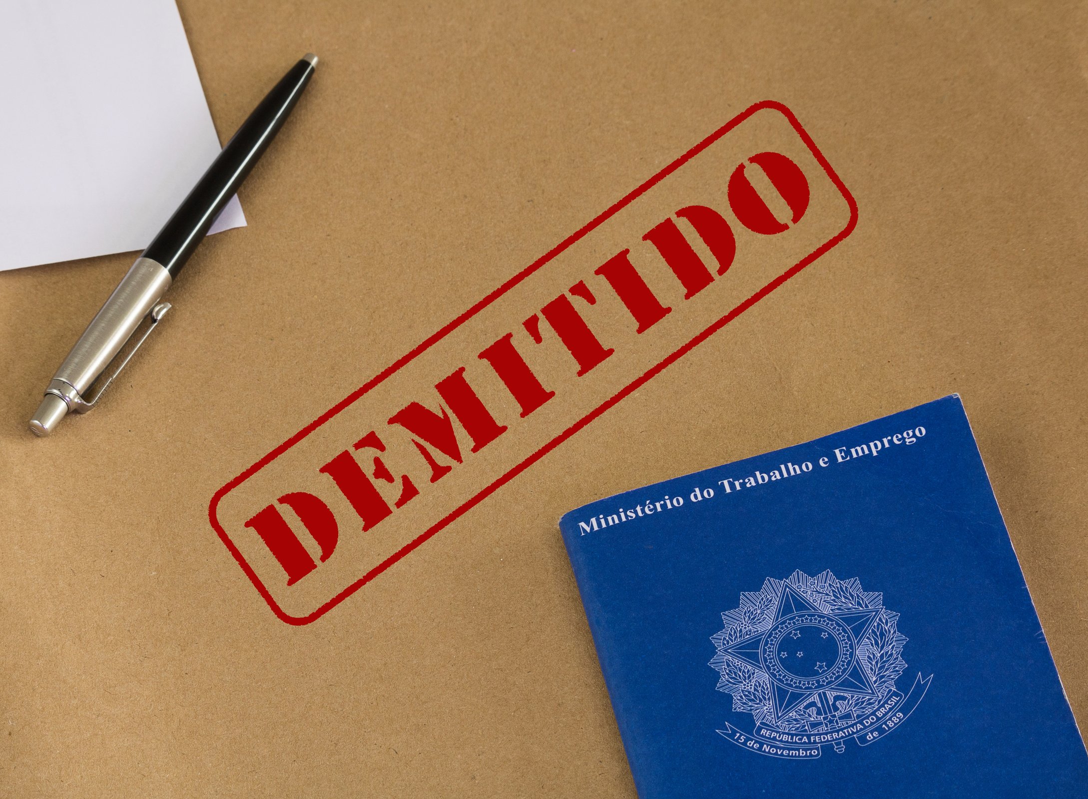 Portfolio work permit of 'Ministry of Labor and Social Security of Brazil - CTPS' (translation) and pen on brown paper envelope with fired stamp (translation: fired)